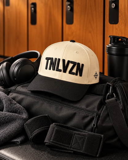 TNLVZN Snapback V1 on a gym bag beside headphones in a locker room